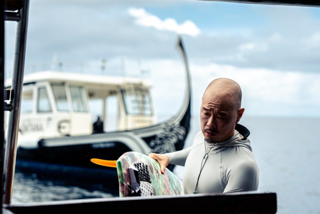 Surfer preparing his board aboard a boat
