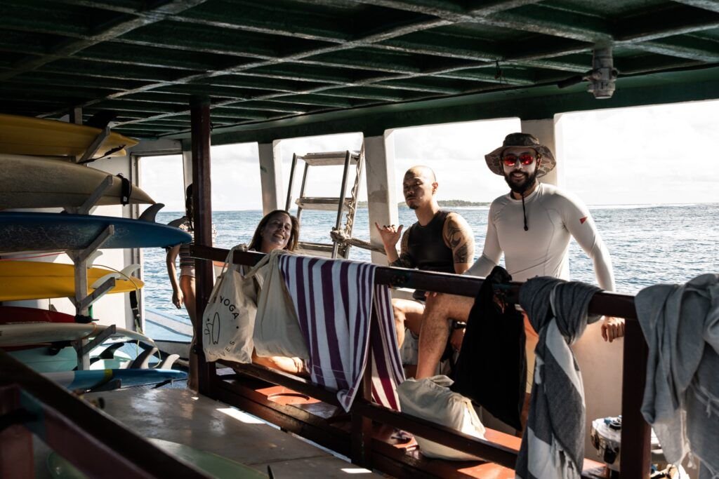 Surfers relaxing aboard a boat with surfboards