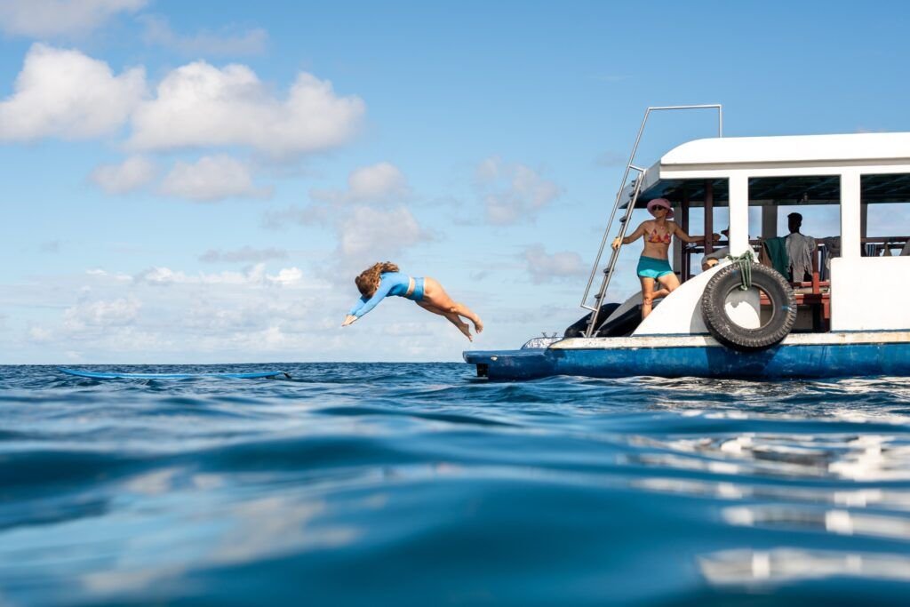 Person diving from a surf boat into blue water